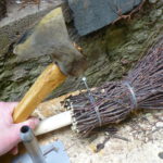 Hammering in nail to hold twig bundle to handle